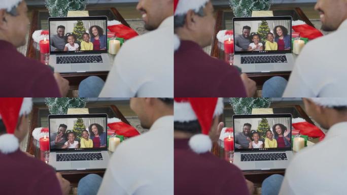 微笑的混血儿父亲和儿子使用笔记本电脑与家人在屏幕上进行圣诞节视频通话