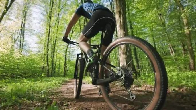 一名骑自行车的人正在穿过森林。他踩得很快。他穿着自行车装备。摄像机在他周围移动。4K 50fps