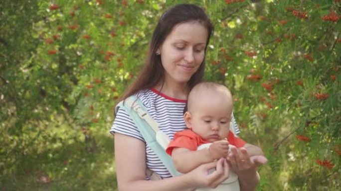 妈妈带着一个新生儿在公园里散步，婴儿被吊在吊袋里，吊袋是一种专门为孩子准备的手提袋。小绿苹果在宝宝的