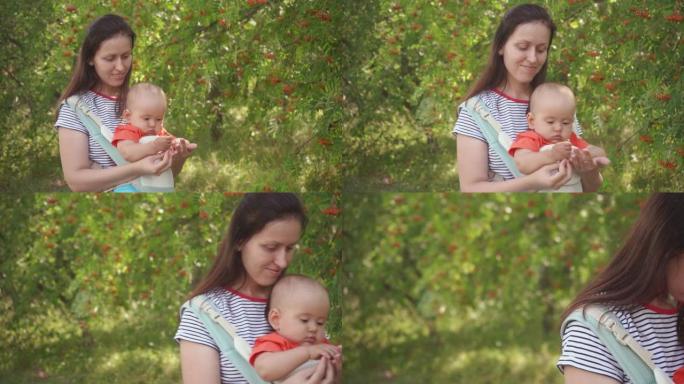 妈妈带着一个新生儿在公园里散步，婴儿被吊在吊袋里，吊袋是一种专门为孩子准备的手提袋。小绿苹果在宝宝的