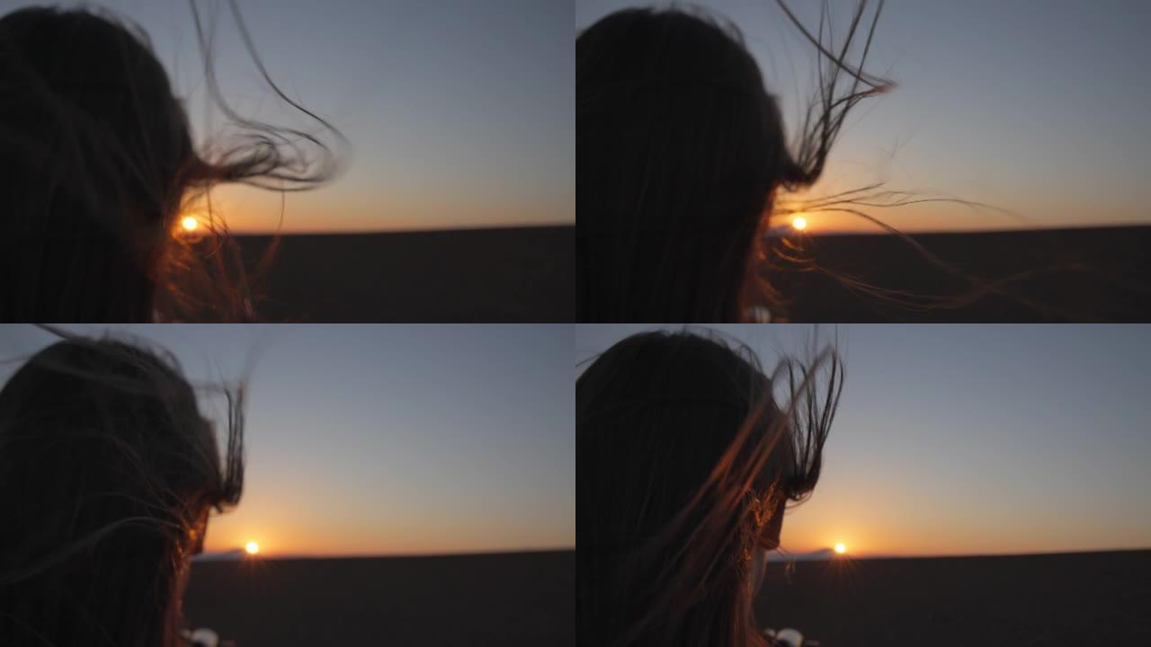 女人的头发在日落时随风吹动