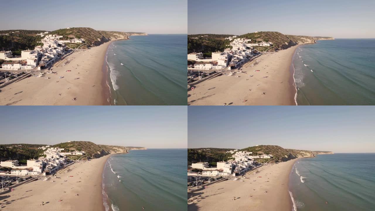 海浪在萨勒马的沙滩上冲刷。葡萄牙阿尔加维的白色联排别墅沿海村庄，空中撤退