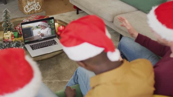拥有圣诞老人帽子的多元化家庭使用笔记本电脑进行圣诞节视频通话，屏幕上有高加索男孩