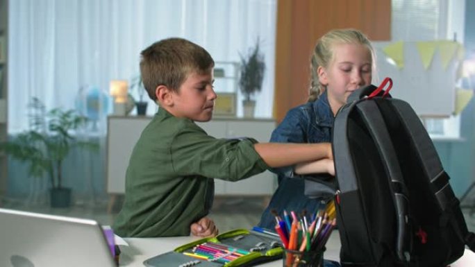 准备上学的孩子，哥哥和姐姐用背包里的彩色铅笔打包书和文具盒