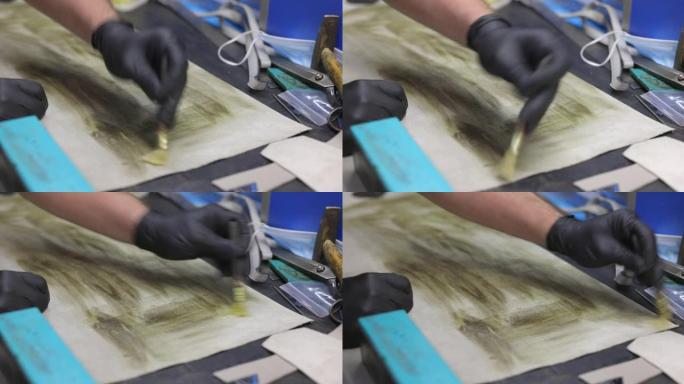 在工艺品修理店的工作台上用刷子将胶水涂在皮片上
