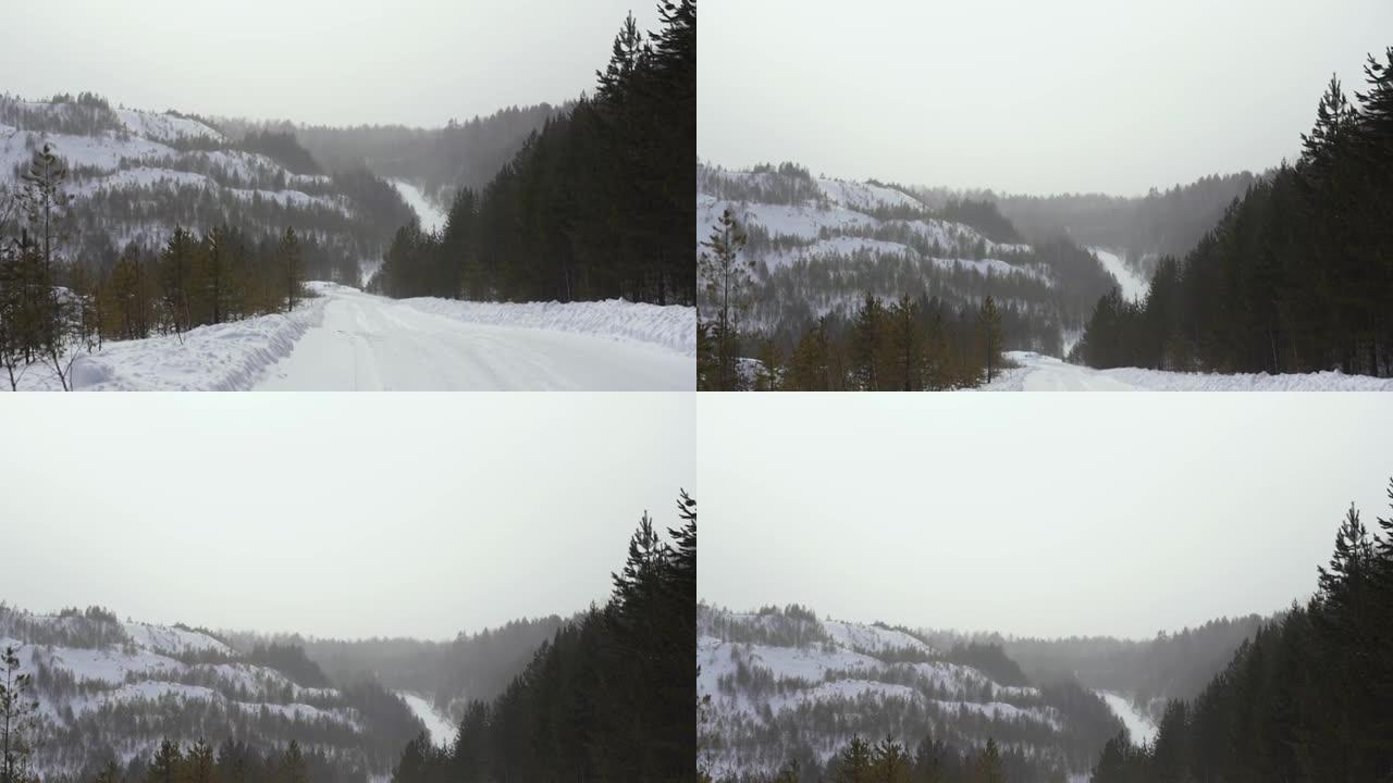 在阴天的冬日，在山腰上查看冬季道路。镜头。冬季旧采石场沿路径的暴风雪的第一人称视角