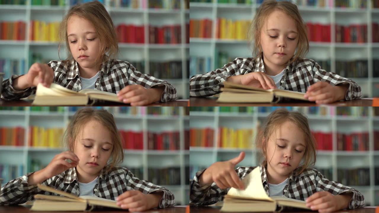 严肃的小学生小学生的特写镜头前视图翻过书页，坐在桌子旁看书，背景模糊。