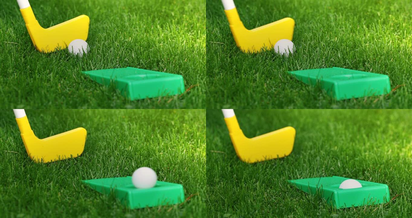 玩具迷你高尔夫-用塑料推杆在绿草地上将球击入洞中