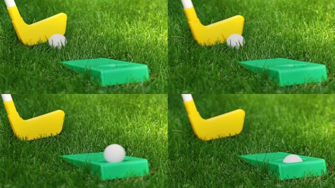 玩具迷你高尔夫-用塑料推杆在绿草地上将球击入洞中