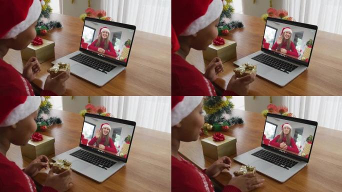 戴着圣诞老人帽子的非裔美国妇女使用笔记本电脑进行圣诞节视频通话，屏幕上有妇女