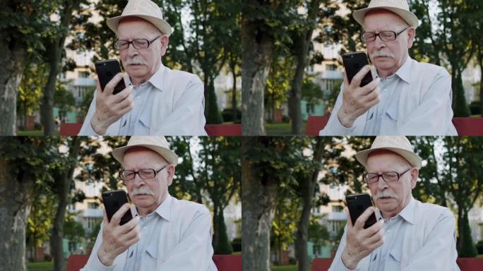 体贴的戴眼镜的老人在公园的手机摄像头上认真聊天