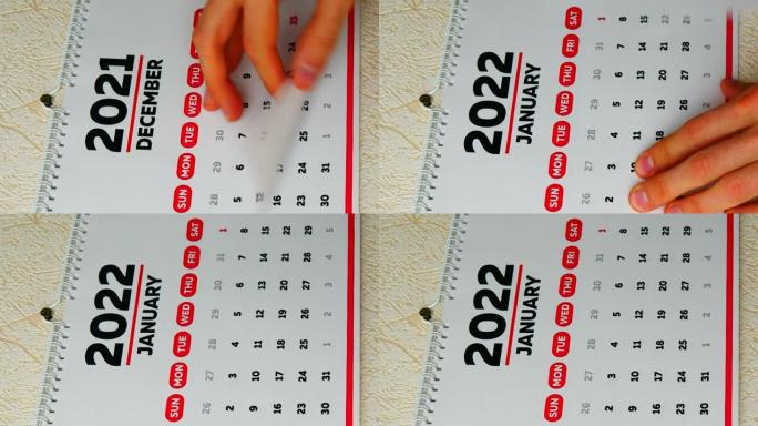 一个男人的手的特写镜头撕下墙上2021日历的12月页，然后是新2022日历的1月页。垂直视频