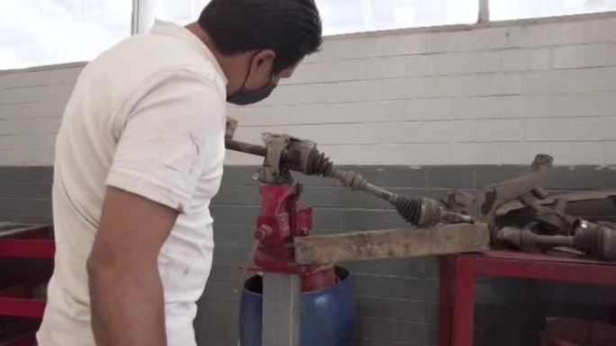 拉丁美洲的拉丁美洲男性技术员在墨西哥的车间车库为汽车的驱动轴提供服务
