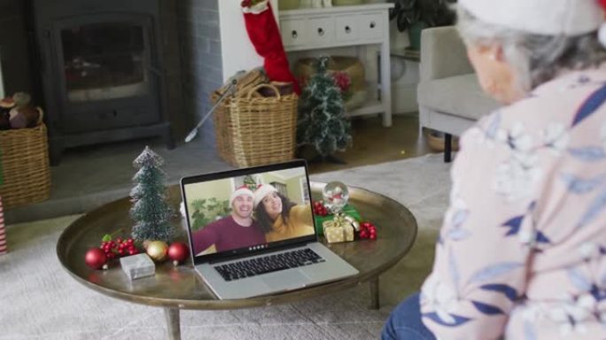 白人高级妇女使用笔记本电脑进行圣诞节视频通话，屏幕上有微笑的情侣