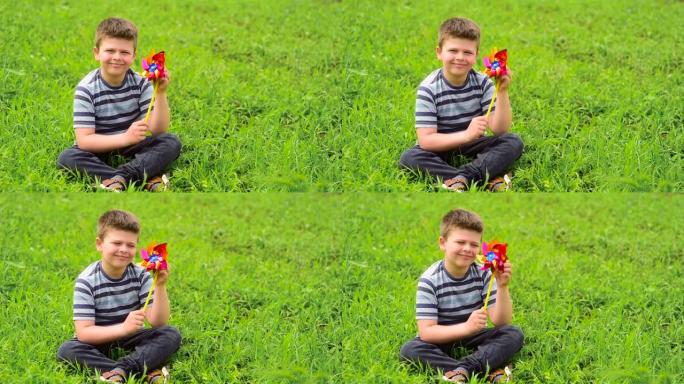 一个开朗，欧洲模样的小男孩坐在绿色的田野里，手里拿着一个儿童转盘
