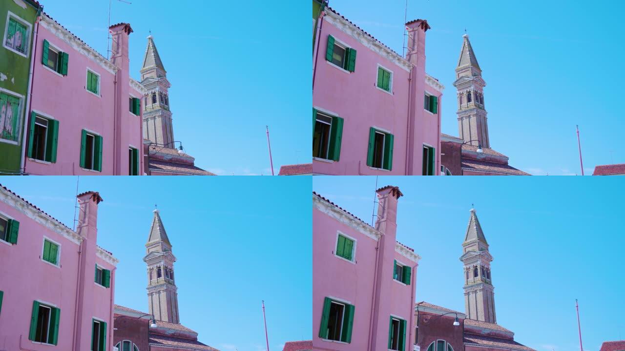 从色彩鲜艳的房子后面看到的教堂钟楼