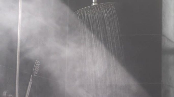 温暖的水流在灰色瓷砖淋浴中产生热蒸汽