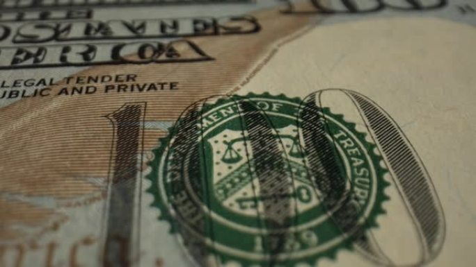 钞票位于桌子的深色表面上，正面朝上。有效的防伪措施适用于该法案。一百美元。