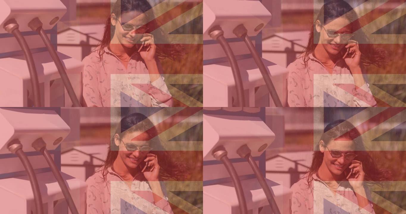 英国国旗对微笑的白人妇女使用智能手机和电动汽车充电