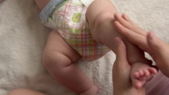 健康护肤，发展儿科学，婴儿近身妈妈双手给裸婴婴儿在手臂、腿部、手指上进行小儿按摩，在足部反射运动，在