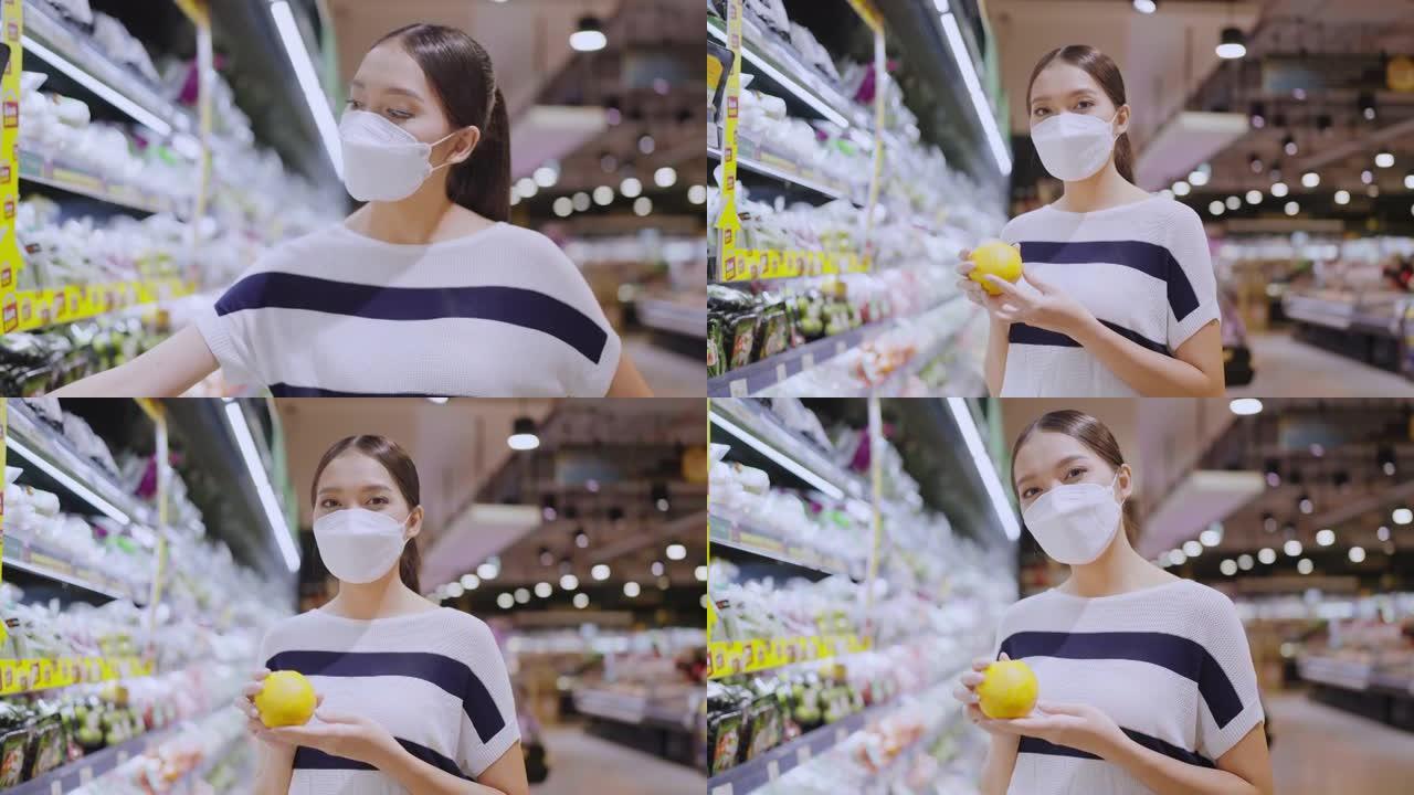 年轻的亚洲女性戴着保护性口罩手在杂货店百货商场选择新鲜产品或消费品，小心愉快的新的正常购物生活方式。