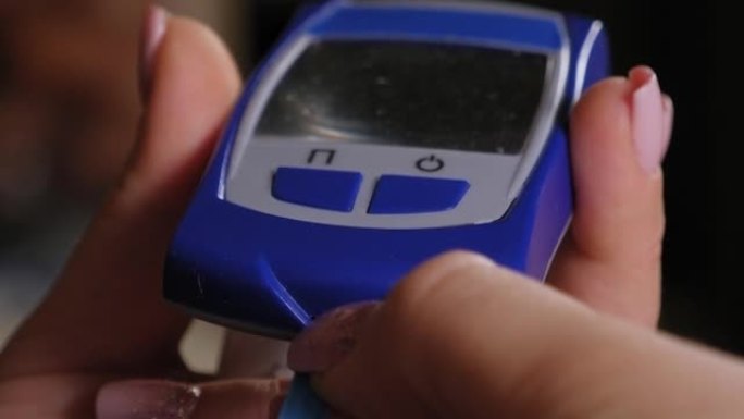 女人用血糖仪和试纸的手的特写。主题糖尿病。