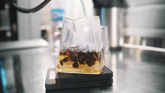 茶饮料。特制果茶。特写。茶师将沸水倒入不同成分的玻璃茶壶中。不含咖啡因的热饮