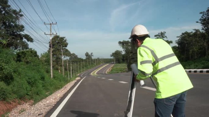 在阳光明媚的日子里，道路背景是经纬仪在公路上的测量员工程师。