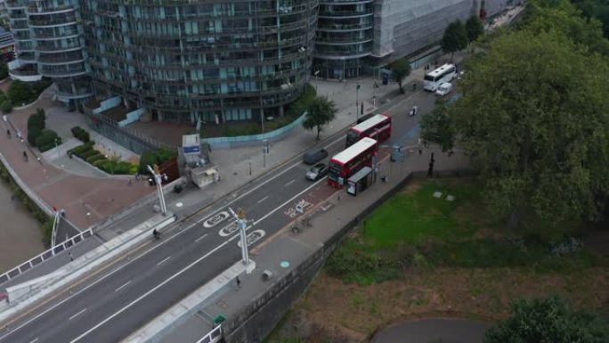 街道上交通的下降镜头。提供公共交通的典型红色双层。沿街的现代公寓楼。英国伦敦