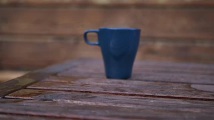 一个成年男子的手在木桌上拿了两个杯子和热咖啡