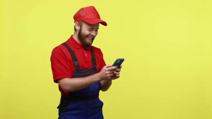 快乐微笑的工人使用手机和笑声的侧视图，为他的客户输入信息。