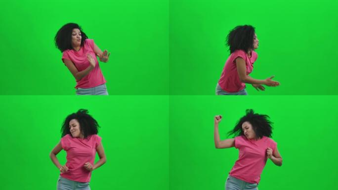 年轻女性非洲裔美国人的肖像欢快地跳着胜利、快乐或好心情的舞蹈。卷发的黑人妇女在工作室的绿色屏幕上摆姿