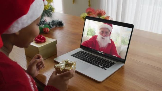 戴着圣诞老人帽子的非洲裔美国妇女使用笔记本电脑进行圣诞节视频通话，屏幕上有圣诞老人