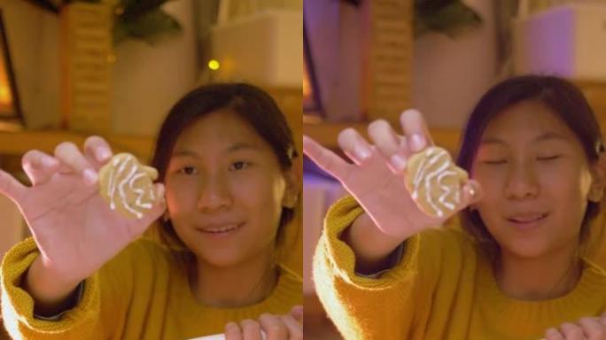 快乐的亚洲女孩展示她的万圣节装饰概念糖霜饼干。