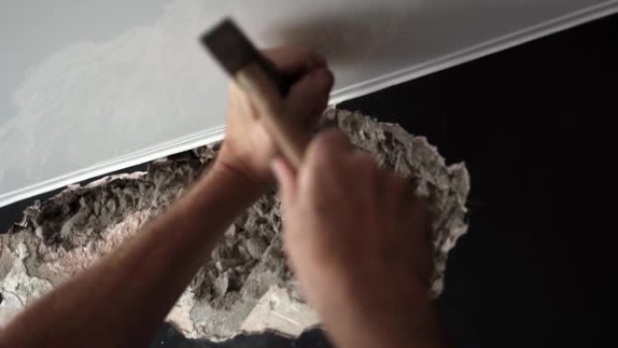 男子在家中进行维修，并用锤子和凿子摧毁混凝土墙。慢动作