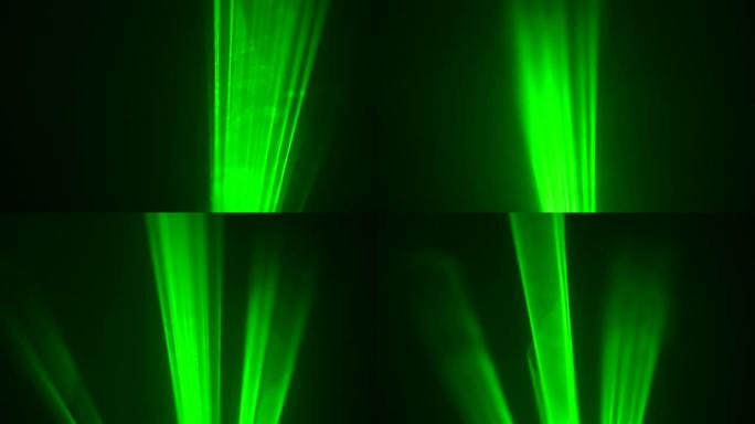 黑色工作室背景上的彩色绿色霓虹灯在烟雾中旋转。激光全息图转动并发出光束。设计、舞台照明、表演、迪斯科