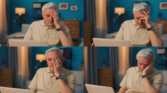 一个疲惫，破碎，辞职，全神贯注的老人坐在笔记本电脑，计算机前，用手盖脸。悲伤的高级商人沉迷于工作量