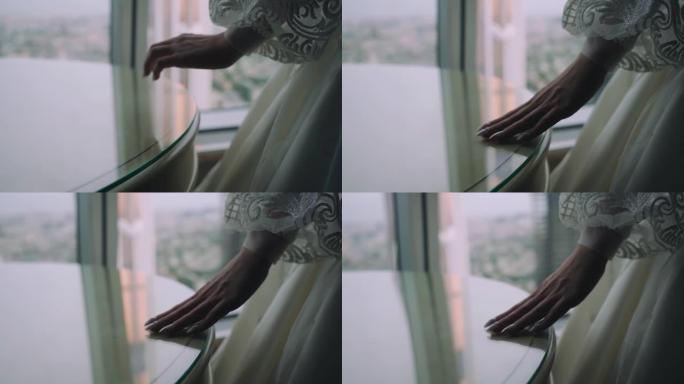 女孩用手触摸窗户旁边桌子的玻璃表面。特写手拍