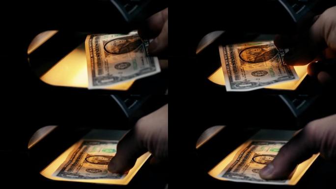 用验钞机检查美元钞票。探测钞票。假币。紫外线下的钱。钞票上的水印。