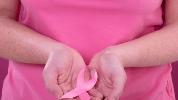 白人妇女手持粉红癌症意识彩带的上腹部视频
