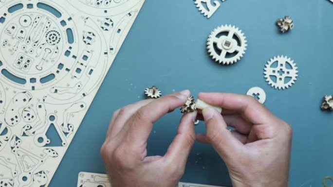 男性手用蜡组装机械齿轮木制玩具。桌上的拼图玩具。游戏休闲活动