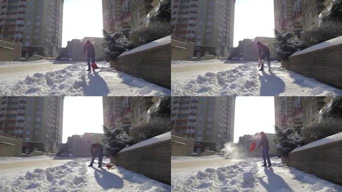 一个男人在院子里晴朗的晴天打扫雪。那家伙用铁锹手动从街上铲起白雪。冬季工作和清除深层积雪，铲起，扔在