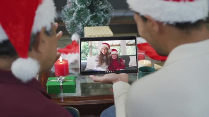 混血儿的父亲和儿子挥舞着，并在屏幕上与家人一起使用平板电脑进行圣诞节视频通话