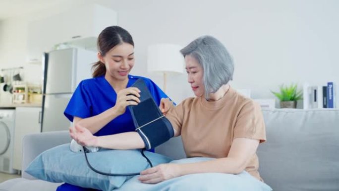 亚洲护理医生检查老年患者使用血压计。疗养院的年轻女治疗师护士照顾老年妇女坐在沙发上。医疗保险服务理念