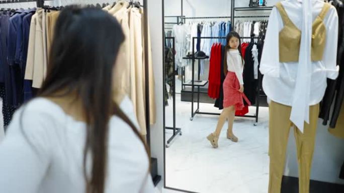 亚洲女性在时装店的镜子里看着自己