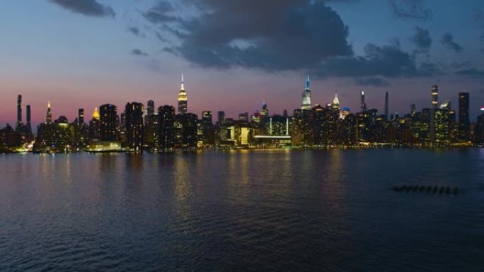 日落时分，纽约曼哈顿中城，东河对面的远处全景夜景。带有转发摄像机运动的航空视频。