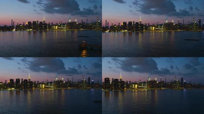 日落时分，纽约曼哈顿中城，东河对面的远处全景夜景。带有转发摄像机运动的航空视频。