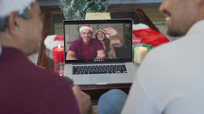 微笑的混血儿父子使用笔记本电脑与屏幕上的情侣进行圣诞节视频通话