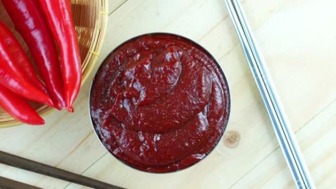 韩国辣椒酱和红辣椒放在木盘上，韩国传统辣椒酱放在木桌背景上。