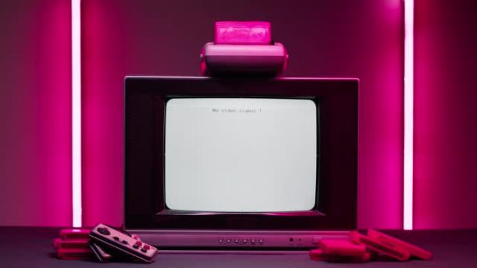 粉红色霓虹灯背景下的白色屏幕旧电视。复古playstation老式电视和墨盒的特写镜头。古董视频游戏